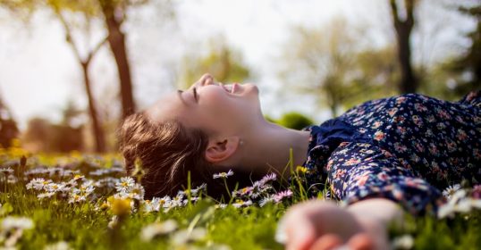 Frau liegt auf einer Blumenwiese